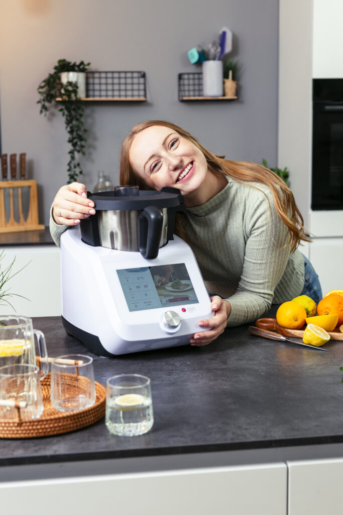 Isy aus dem Zaubermix Team umarmt einen Monsieur Cuisine in einer Küche