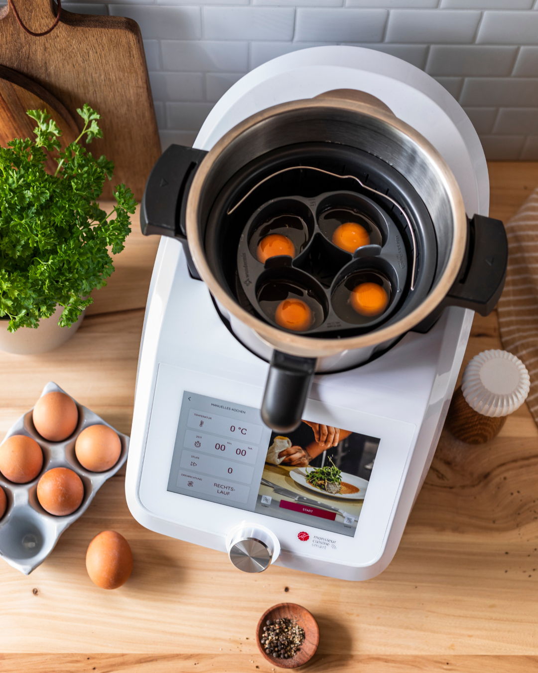 ein schwarzer Einsatz im Monsieur cuisine mixbehälter, in dem vier eier liegen